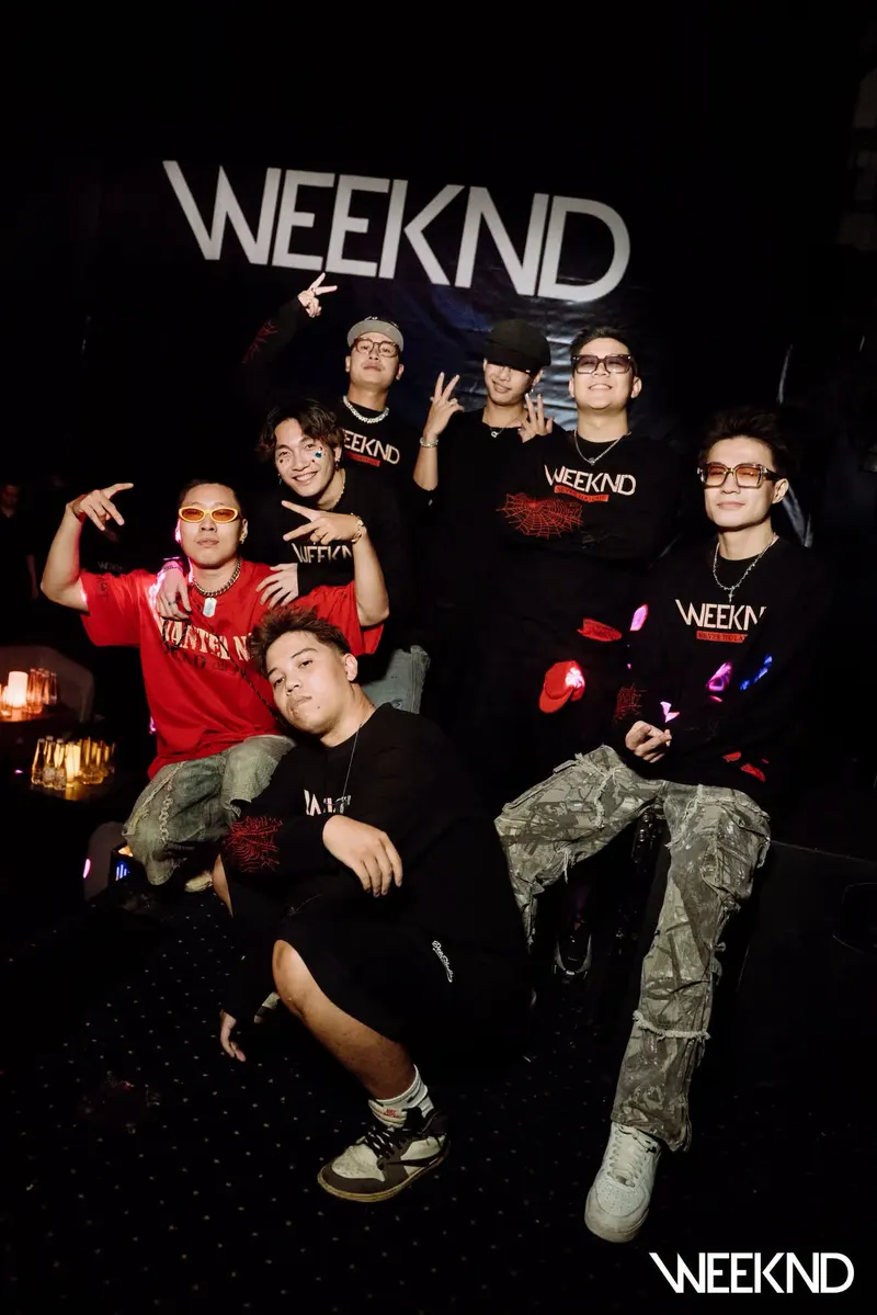 Nhóm khách chụp ảnh trước phông nền wordmark WEEKND